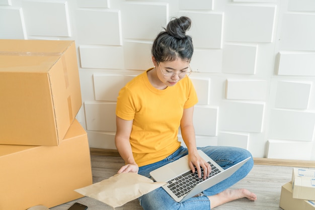 Aziatische vrouw die in de leveringsdienst werken met laptop