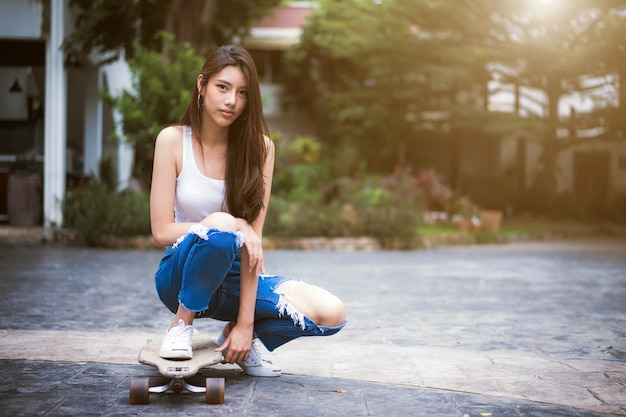 Aziatische vrouw die lacht blij met skateboard / longboard