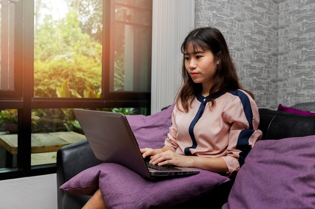 Aziatische vrouw die laptop computer met behulp van terwijl het zitten in een uitstekende koffiewinkel