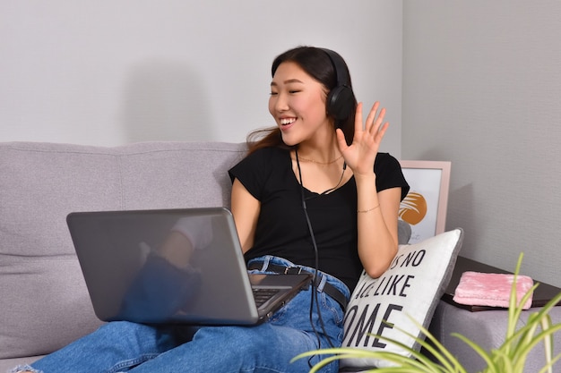 Aziatische vrouw die laptop op bank met behulp van