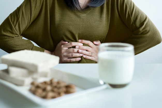 Foto aziatische vrouw die maagpijn met een glas melk heeft