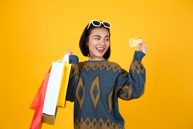 Aziatische vrouw die met glazen kleurrijke document zakken en een creditcard houdt