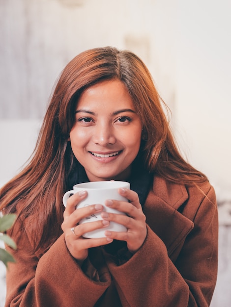 Aziatische vrouw die met laptop in koffiewinkel werkt.