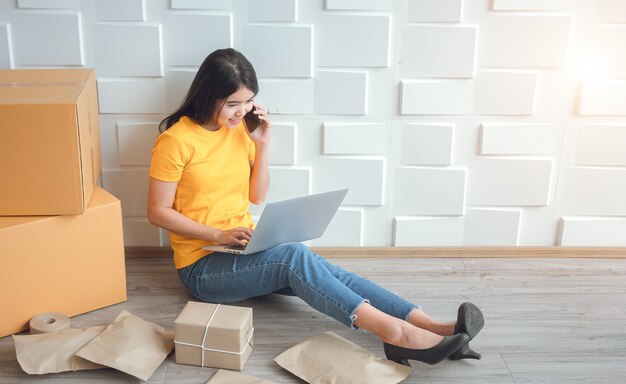 Aziatische vrouw die op zoek is naar bestelgegevens en apparatuur op laptops en mobiele telefoons controleert