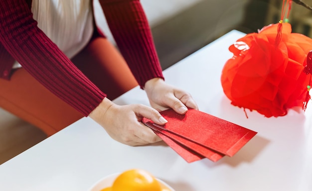 Aziatische vrouw die rode envelop geeft voor nieuwe maanjaarvieringen Houd het rode pakje vast