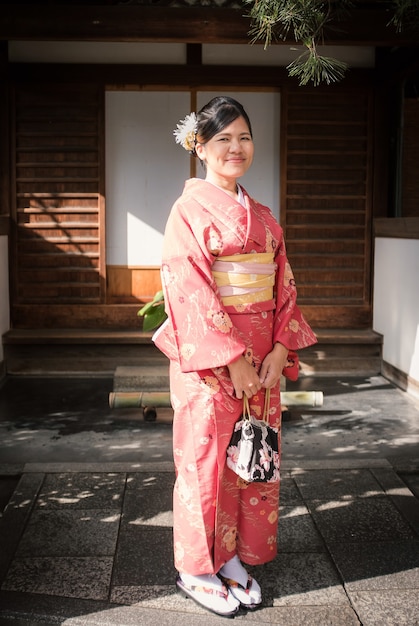 Aziatische vrouw die rode kimono in Kyoto draagt