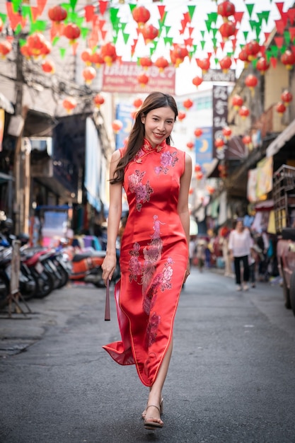 Aziatische vrouw die rode kleding Cheongsam draagt bij de stad van China. Chinees Nieuwjaar concept.