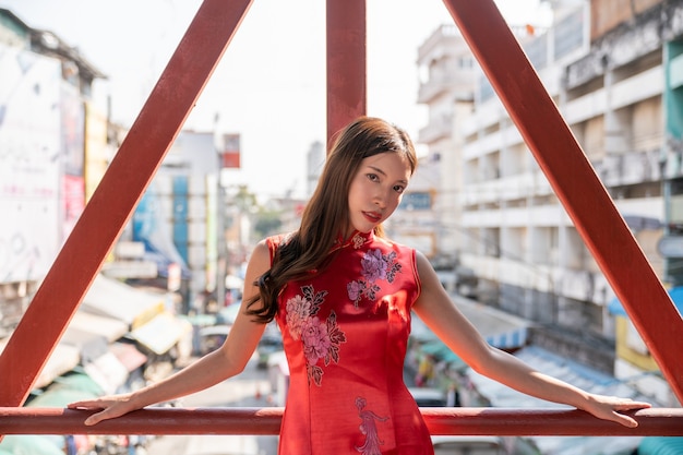 Aziatische vrouw die rode kleding Cheongsam draagt bij de stad van China. Chinees Nieuwjaar concept.