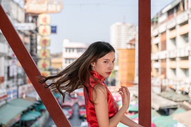 Aziatische vrouw die rode kleding Cheongsam draagt bij de stad van China. Chinees Nieuwjaar concept.