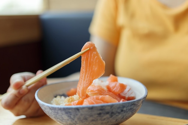 Aziatische vrouw die sashimi van de zalmplak met rijst eet in Japans restaurant