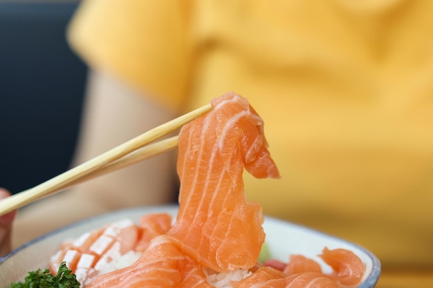 Aziatische vrouw die sashimi van de zalmplak met rijst eet in Japans restaurant