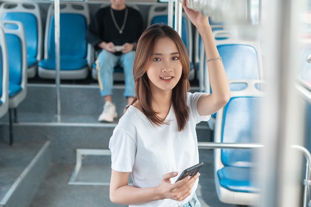 Aziatische vrouw die smartphone op bus gebruikt