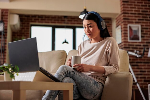 Foto aziatische vrouw die thuis kijkt naar online filmstreamingabonnementsplatform, entertainmentfilmseries internetwebtechnologie die nieuwe media digitale app op laptop uitzendt