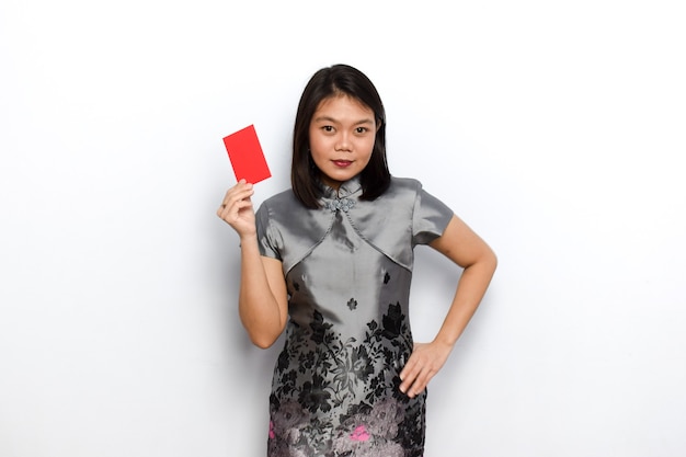 Aziatische vrouw die traditionele cheongsam gebruikt die rode envelop toont en vasthoudt Angpau Geef het aan jou