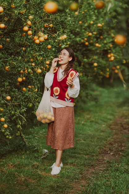 Aziatische vrouw die vrolijk sinaasappels in de tuin plukt