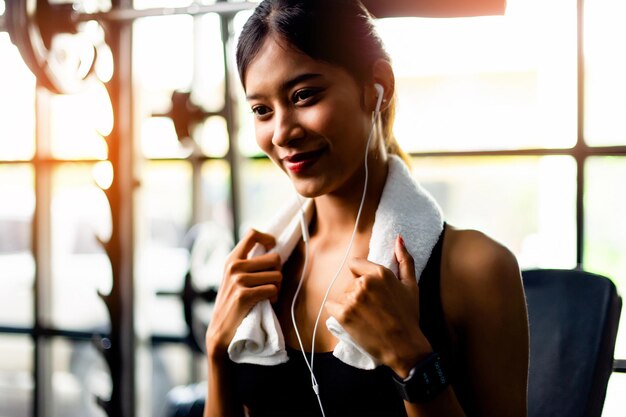 Aziatische vrouw die witte trainingskleding draagt en een koptelefoon draagt, ontspant tijdens het sporten en creëert energie voor inspiratie voor fitness