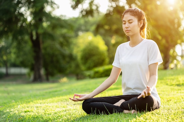 Aziatische vrouw die yogaoefeningen in het park doet