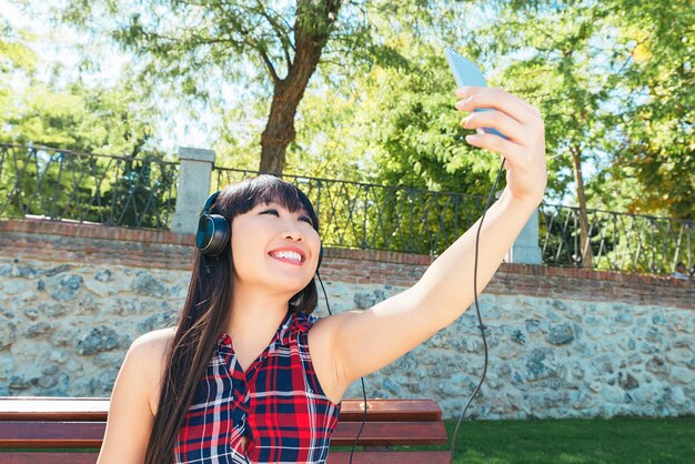 Aziatische vrouw die zelfportret selfie foto op park neemt. Ze is gelukkig