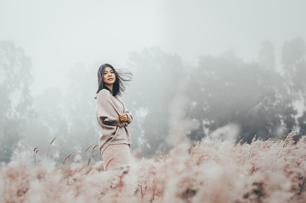 Aziatische vrouw die zich in ingediende grasbloem dekking met mist bevinden