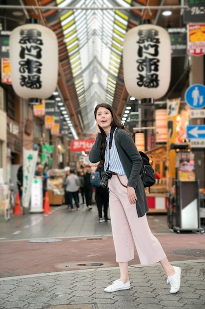 aziatische vrouw die zich opgewonden voelt om de markt te bezoeken. Vertaling op achtergrond lantaarns tekst "Kuromon Market".