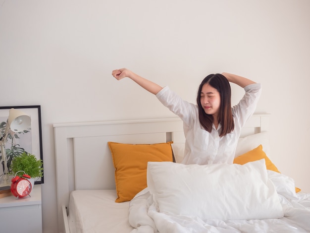 Aziatische vrouw die zich uitstrekt in bed na wakker worden