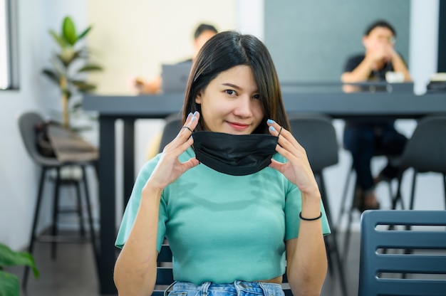 Foto aziatische vrouw die zwart medisch masker draagt