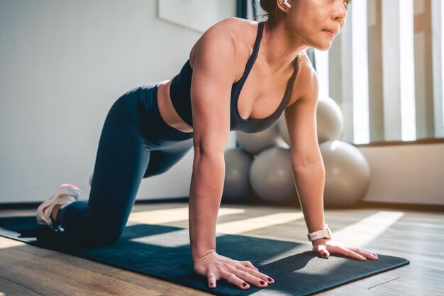 Foto aziatische vrouw doet plank en strek benen en armen op yogamat in gym in de ochtendoefening workout en fitness lifestyle concepten