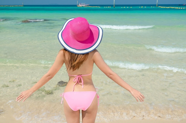 Aziatische vrouw draagt een roze bikini op het strand