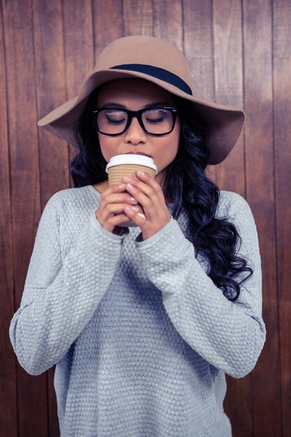 Aziatische vrouw drinken door wegwerp cup tegen houten muur