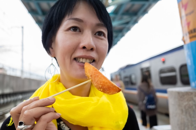 Aziatische vrouw eet Taiwanese zoete frietjes in een stad