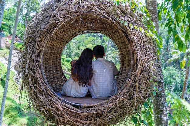 Aziatische vrouw en man genieten van zijn tijd zittend op een vogelnest in de tropische jungle in de buurt van de rijstterrassen op het eiland Bali, Indonesië. Natuur- en reisconcept