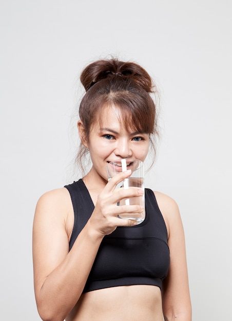 Aziatische vrouw fitness suit in de hand houden van een glas water