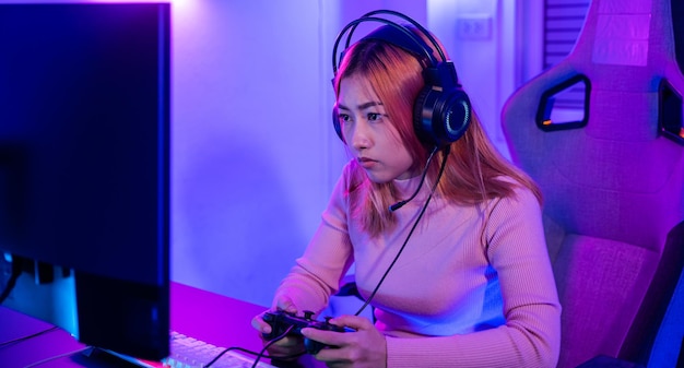 Aziatische vrouw gamer met gaming-hoofdtelefoon met joystickconsole om videogame te spelen en online te streamen op computer Pc neonlicht thuis toernooispeler ESport-concept