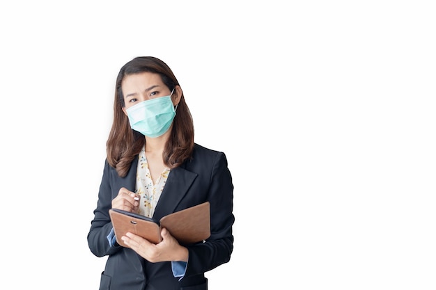 Foto aziatische vrouw gebruikt een tablet om thuis te werken en draagt een antivirusmasker om anderen te beschermen tegen het coronavirus