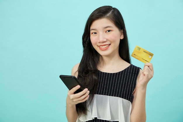Aziatische vrouw gebruikt smartphone- en creditcardbetalingen online online winkelen op blauwe achtergrond