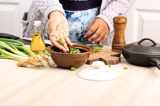 Aziatische vrouw giet groene lente-ui naar de kom op houten tafel, stap voor stap koken in de keuken, geselecteerde focus met kopie ruimte