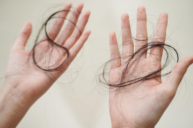Aziatische vrouw heeft een probleem met lang haarverlies in haar hand