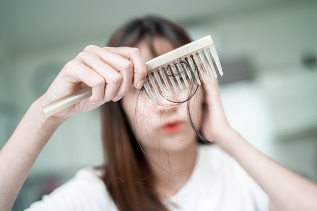 Aziatische vrouw heeft problemen met lang haarverlies, hecht aan kamborstel