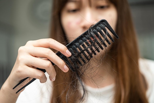 Aziatische vrouw heeft problemen met lang haarverlies, hecht aan kamborstel