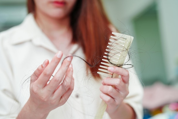 Aziatische vrouw heeft problemen met lang haarverlies, hecht aan kamborstel