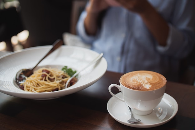 Aziatische vrouw het drinken koffie en het werken met laptop computer in koffie