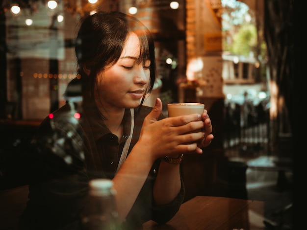 Aziatische vrouw het drinken koffie in de koffie van de koffiewinkel