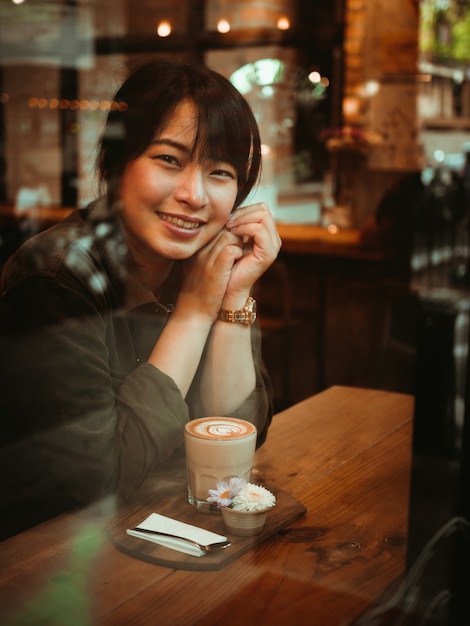 Aziatische vrouw het drinken koffie in de koffie van de koffiewinkel