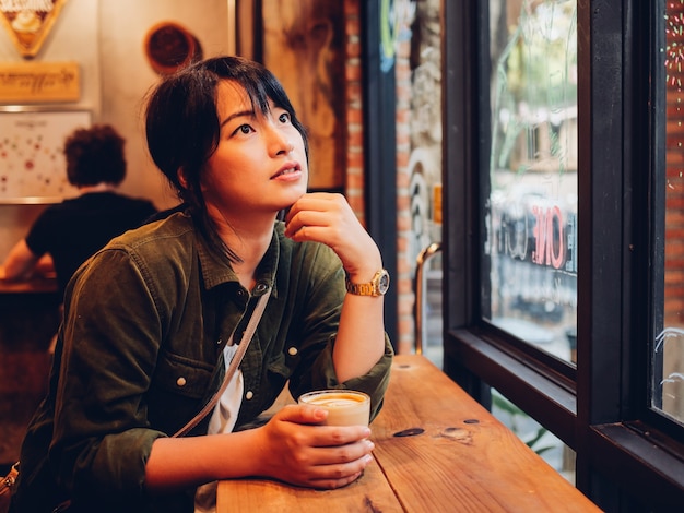 Aziatische vrouw het drinken koffie in de koffie van de koffiewinkel