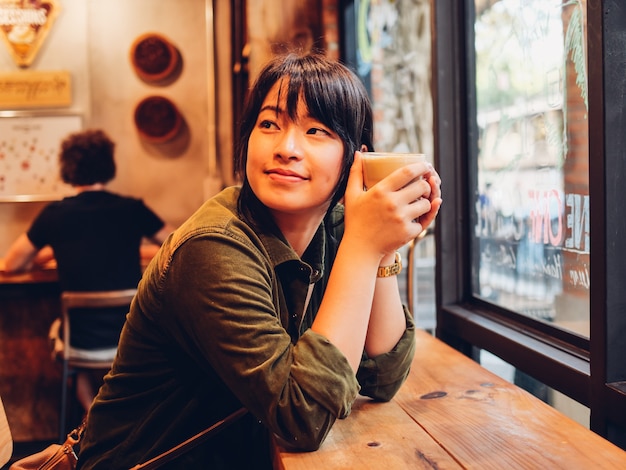 Aziatische vrouw het drinken koffie in de koffie van de koffiewinkel