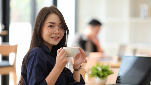 Aziatische vrouw het drinken koffie in een bureau