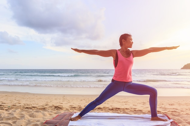 Aziatische vrouw het spelen Yoga en oefening op het tropische strand in Thailand