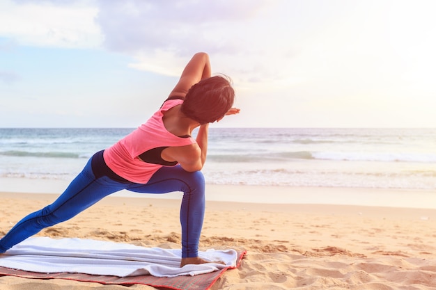 Aziatische vrouw het spelen Yoga en oefening op het tropische strand in Thailand