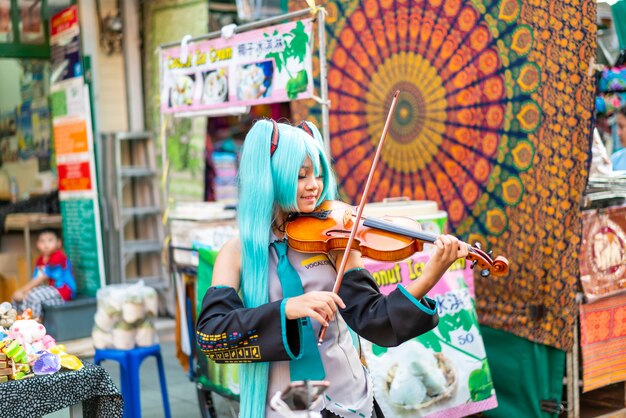 Aziatische vrouw in cosplay kostuum viool spelen op Khao Sarn Road