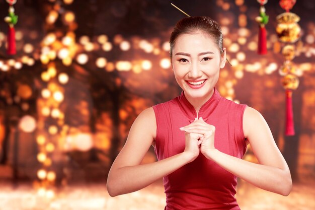 Aziatische vrouw in een cheongsam jurk met gefeliciteerd gebaar